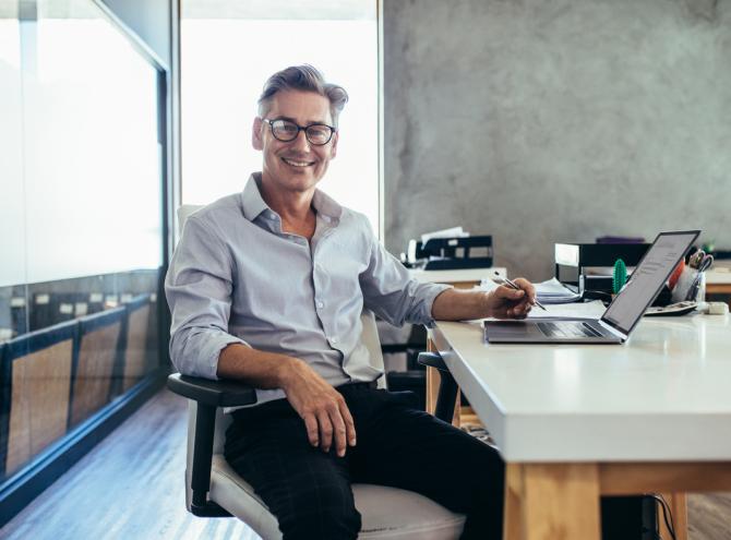 Businessman sitting at table with laptop. 